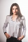 Giovane donna in camicia a righe posa su sfondo grigio — Foto stock