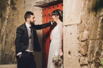 Jeune mariée et marié debout ensemble près du mur — Photo de stock