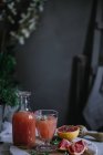 Jus de pamplemousse frais en verre et bouteille avec ingrédient sur la table de cuisine — Photo de stock