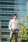Впевнений молодий бізнесмен стоїть проти сучасної будівлі — стокове фото