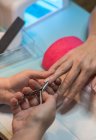 Manikürerin schneidet Nägel von Klientin mit Nagelzange im Schönheitssalon — Stockfoto