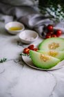 Fette di frutta gustosa con semi che giacciono sul piatto vicino ai pomodorini — Foto stock