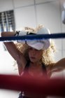 Уставшая фитнес-женщина с вьющимися волосами в спортивной одежде находится в тренажерном зале снизу — стоковое фото