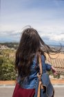 Дівчина з рюкзаком стоїть на пагорбі в місті — стокове фото