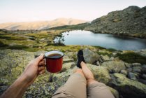 Cropped of man with mug in hand on shore of lake — Stock Photo