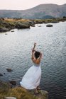 Young woman in white dress standing alone on shore of lake — Stock Photo