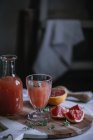 Свежий грейпфрутовый сок в стакане и бутылка с ингредиентом на кухонном столе — стоковое фото