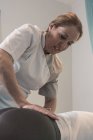 Terapeuta massageando lombos femininos na sala de massagem — Fotografia de Stock