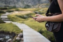 Midsection of woman using smartphone in nature — Stock Photo