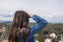 Girl standing on hill and looking at view of town — Stock Photo