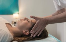 Terapeuta masajeando cara femenina en sala de masajes - foto de stock