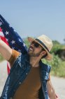 Человек с американским флагом стоит в поле — стоковое фото