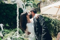 Junges Brautpaar küsst sich bei Hochzeitszeremonie — Stockfoto