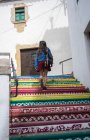 Girl walking up on colorful patterned stairs in town — Stock Photo