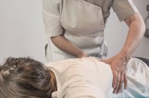 Therapist massaging female loins in massage room — Stock Photo