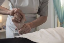 Терапевт масажує жіночу руку в масажному кабінеті — стокове фото