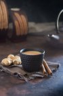 Oriental cup of tea Chai with milk with cinnamon on grey cloth on dark background — Stock Photo