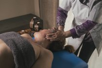 Terapeuta massageando a cabeça feminina na sala de massagem — Fotografia de Stock