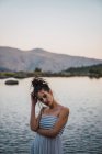Young woman standing alone on shore of lake — Stock Photo