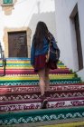 Дівчина піднімається на барвистих візерункових сходах у місті — стокове фото