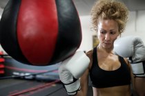 Serious woman training in gym with punching bag — Stock Photo