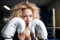 Серйозна жінка тренується в тренажерному залі з мішком для ударів — стокове фото