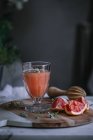 Fresh grapefruit juice in glass on wooden board with ingredient — Stock Photo