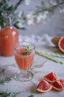 Frischer Grapefruitsaft im Glas mit Zutat auf dem Küchentisch — Stockfoto