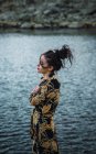 Junge Frau steht allein am Ufer des Sees mit blauem Wasser — Stockfoto