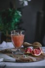 Свіжий грейпфрутовий сік у склянці на дерев'яній дошці з інгредієнтом — стокове фото