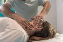 Primo piano del terapeuta massaggiare il viso femminile nella sala massaggi — Foto stock