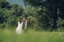 Jeune couple marié marchant dans le bosquet — Photo de stock