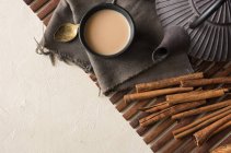 Oriental cup of tea Chai with milk, cinnamon and cardamom on wooden rug — Stock Photo