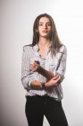 Молода жінка в сорочці і джинсах позує на сірому фоні — стокове фото