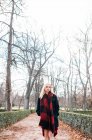 Giovane donna in abito rosso a piedi nel parco — Foto stock