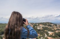 Female tourist taking photo of town from hill — Stock Photo