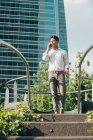 Selbstbewusster junger Geschäftsmann spricht auf dem Smartphone Stufen hinunter — Stockfoto