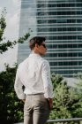 Jeune homme d'affaires en lunettes de soleil debout devant un bâtiment moderne — Photo de stock