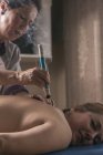 Terapeuta realizando tratamiento de moxibustión en sala de masajes - foto de stock
