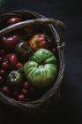 Fresh picked tomatoes in basket on grey background — Stock Photo