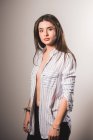 Fille sensuelle à rayures chemise déboutonnée posant sur fond gris — Photo de stock