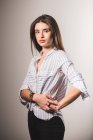 Jeune femme en chemise rayée posant sur fond gris — Photo de stock