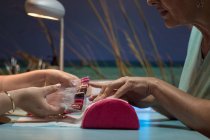 Manucure féminine montrant la palette de vernis à ongles au client dans le salon de beauté — Photo de stock