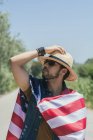 Homem feliz e pulando de alegria com uma bandeira americana em uma estrada solitária — Fotografia de Stock