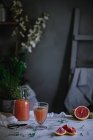Свіжий грейпфрутовий сік у склянці та пляшці на білому мармуровому столі — стокове фото