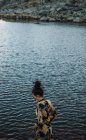 Giovane donna in camicia colorata in piedi da sola sulla riva del lago — Foto stock
