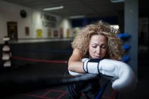 Adult lady in boxing gloves leaning on ring — Stock Photo