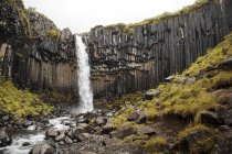 Pintoresca cascada salpicando desde el acantilado rocoso, Islandia - foto de stock
