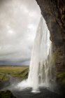Cascada salpicando desde el acantilado de piedra, Islandia - foto de stock