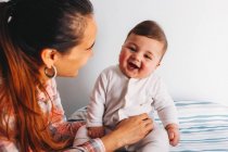 Smiling mother holding funny baby in nursery — Stock Photo